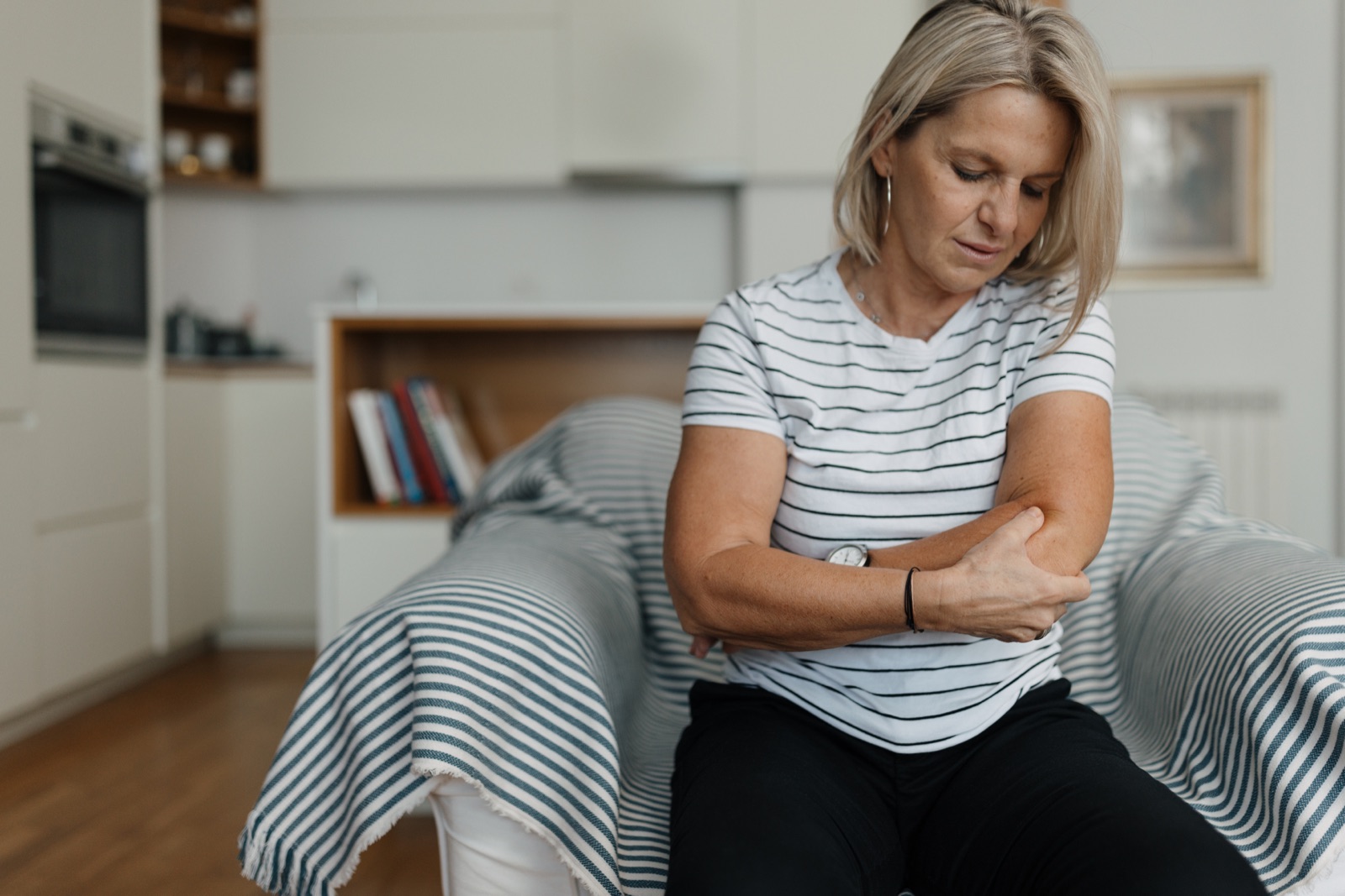 Woman at home holding her elbow during elbow injury treatment