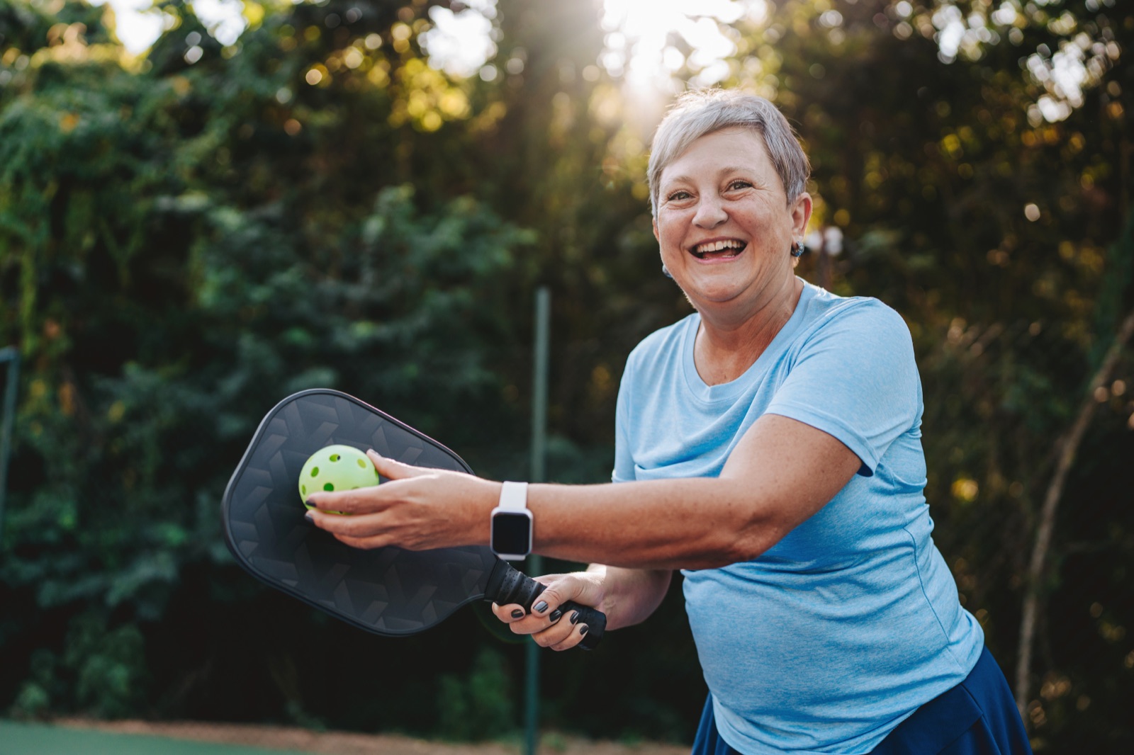 Smiling senior woman playing pickleball after a frozen shoulder recovery