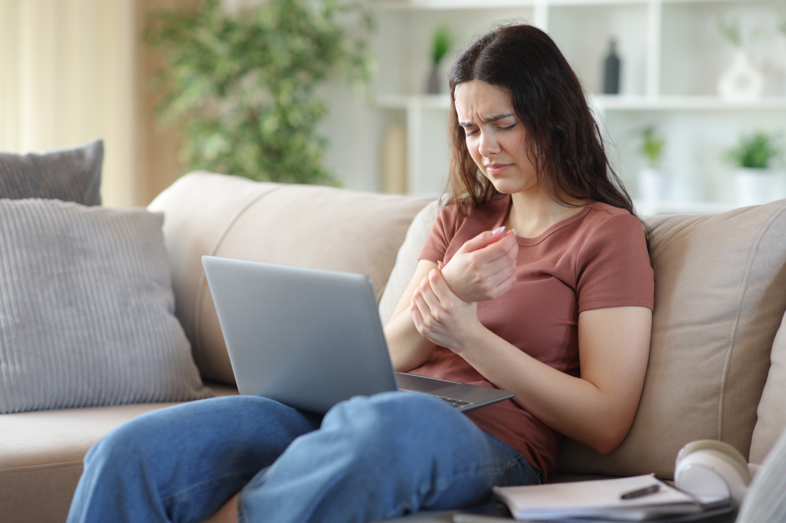 Woman holding her wrist while on a laptop during an online wrist injury consultation